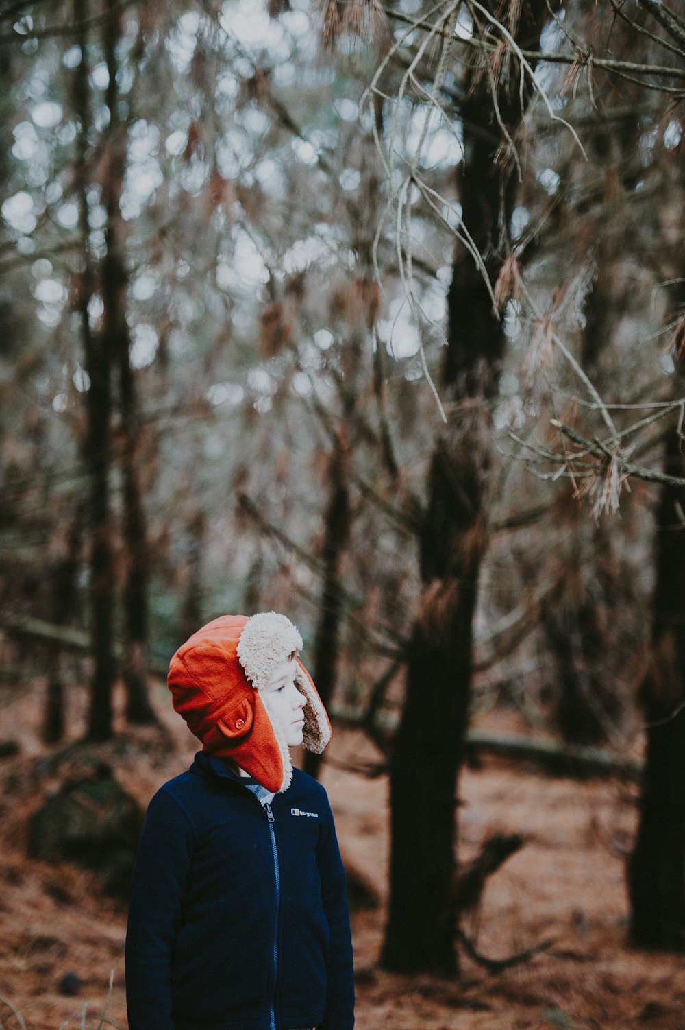 얕은 초점 사진에서 숲 한가운데에 서 있는 사람