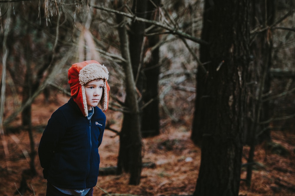 boy wearing aviator hat surrounded by trees