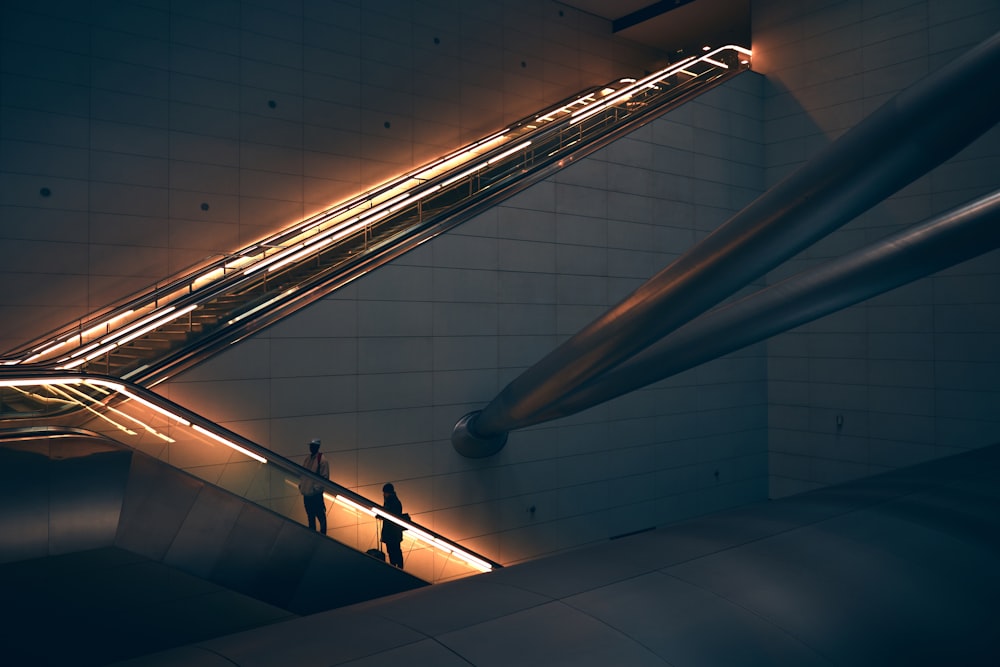 two person standing on escalator