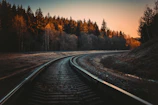 Modern railway track winding through mountainous landscape at sunrise.