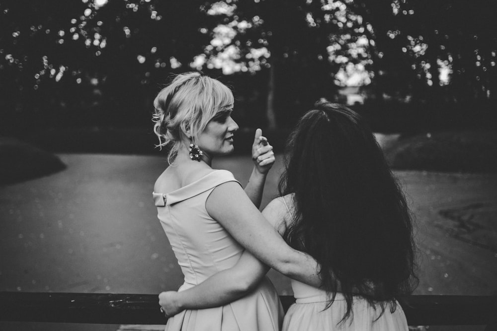 grayscale photography of two women holding each others waist