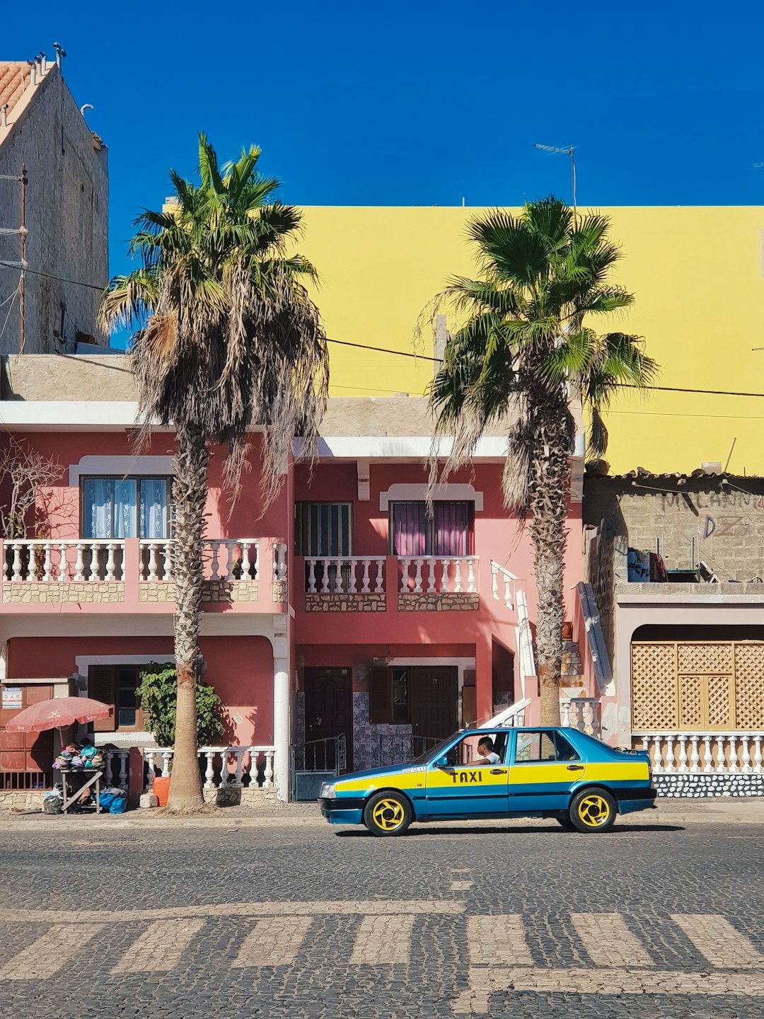 blue and yellow taxi parked near palm tree