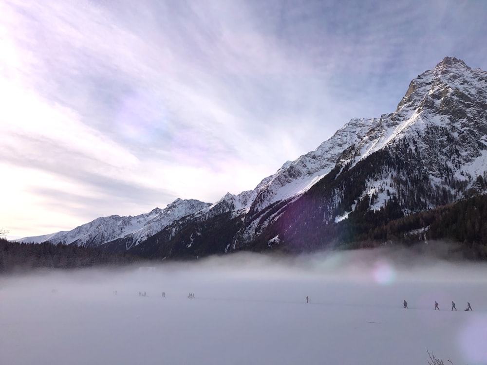 people hiking on snow covered field near glacier mountain during day