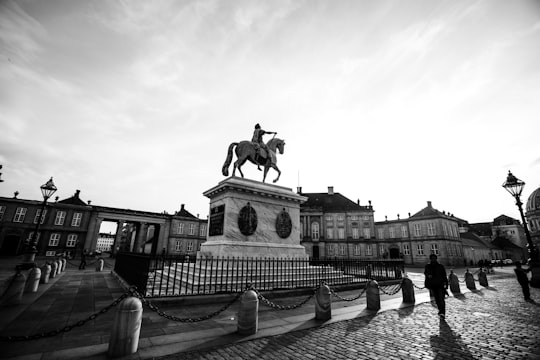 grayscale photo of man riding horse statue in Amalienborg Denmark