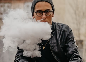 man sitting while vaping in selective focus photography