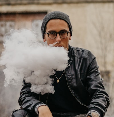 man sitting while vaping in selective focus photography