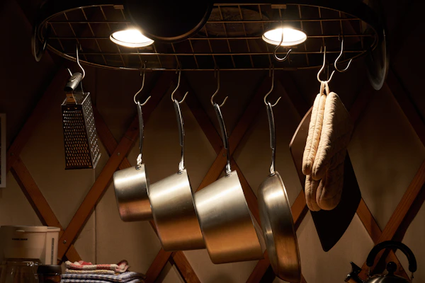 A sleek multi-tier kitchen storage rack neatly holding pots, pans, and utensils in a bright kitchen.