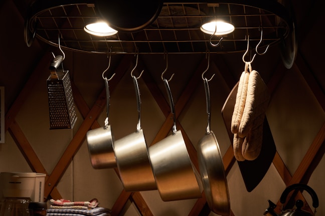 A rustic kitchen featuring a ceiling-mounted pot rack loaded with colorful pots and pans.