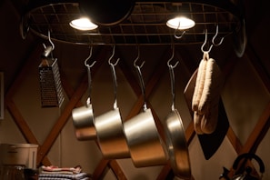 Shiny pots and pans hanging from a kitchen rack with warm lighting.
