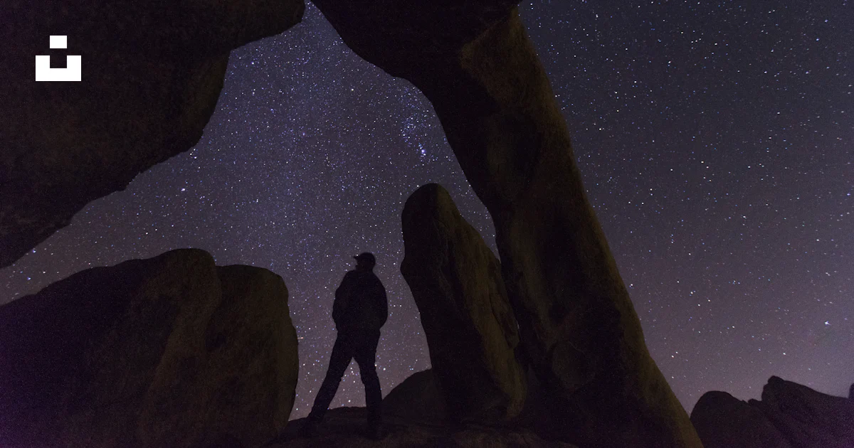 Person Looking Under Rocks Silhouette of person under rock formation at night time photo – Free ...