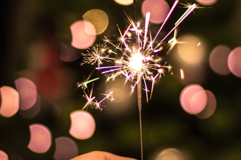 bokeh photography of person holding fireworks