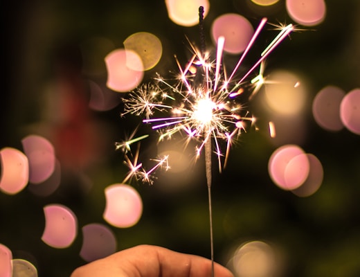 bokeh photography of person holding fireworks