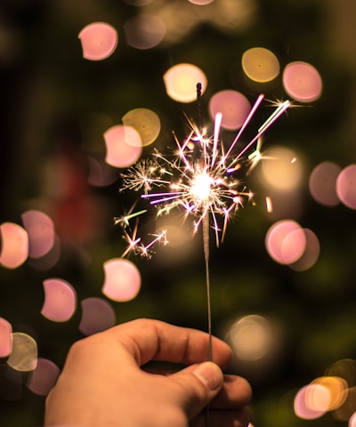 bokeh photography of person holding fireworks