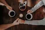 person holding white ceramic mugs