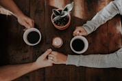 person holding white ceramic mugs