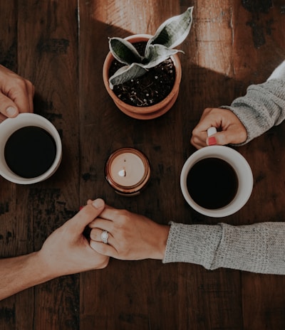 person holding white ceramic mugs