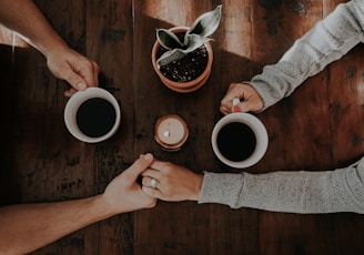 person holding white ceramic mugs