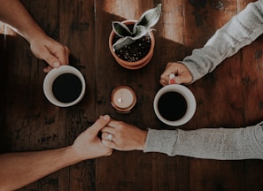 person holding white ceramic mugs