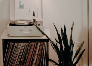 white turntable on white wooden organizer with vinyl record sleeves