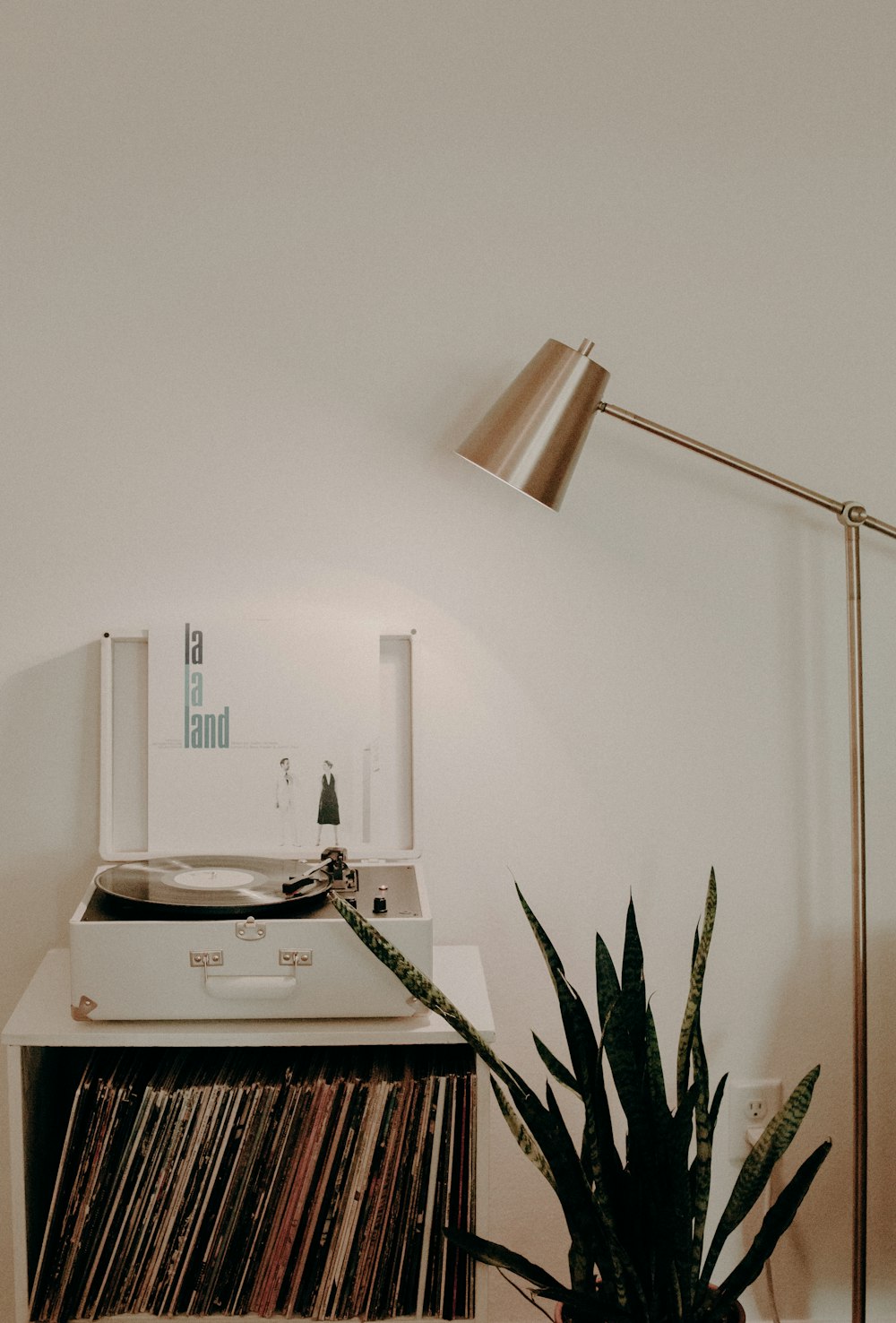 white turntable on white wooden organizer with vinyl record sleeves