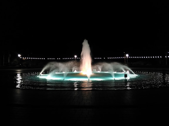 A refined fountain with clean lines, softly glowing against a dark backdrop, creating a peaceful atmosphere.
