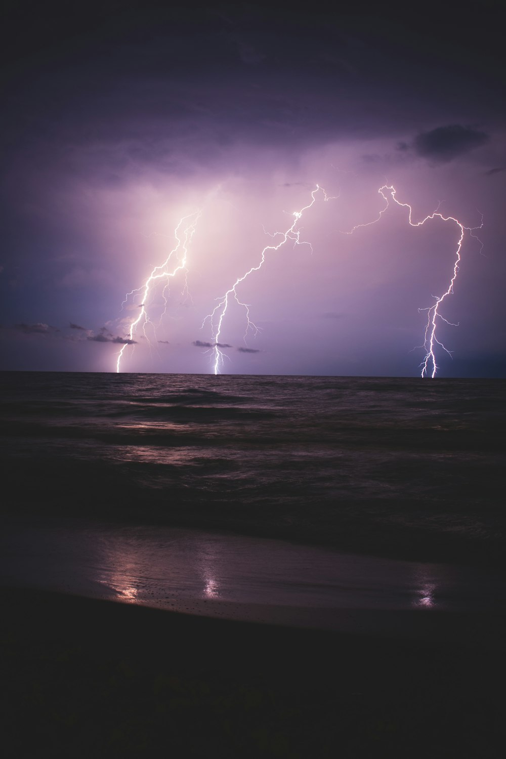 seashore and ocean with lightning during night time