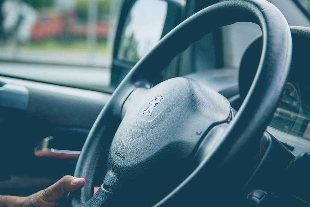 a steering wheel of a car with a hand on the steering wheel