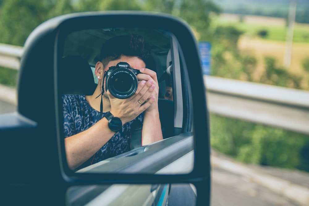 hombre tomando una foto en el espejo retrovisor