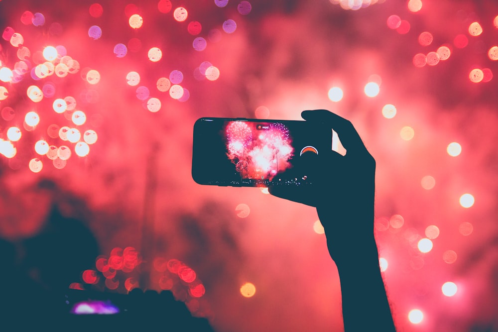 person taking a photo of fireworks using smartphoen