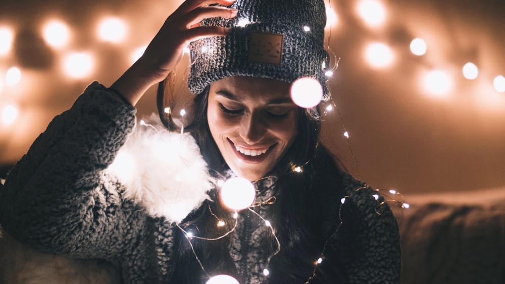 woman in black knit cap holding string lights