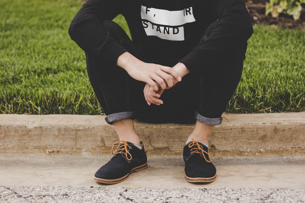 person sitting on sidewalk