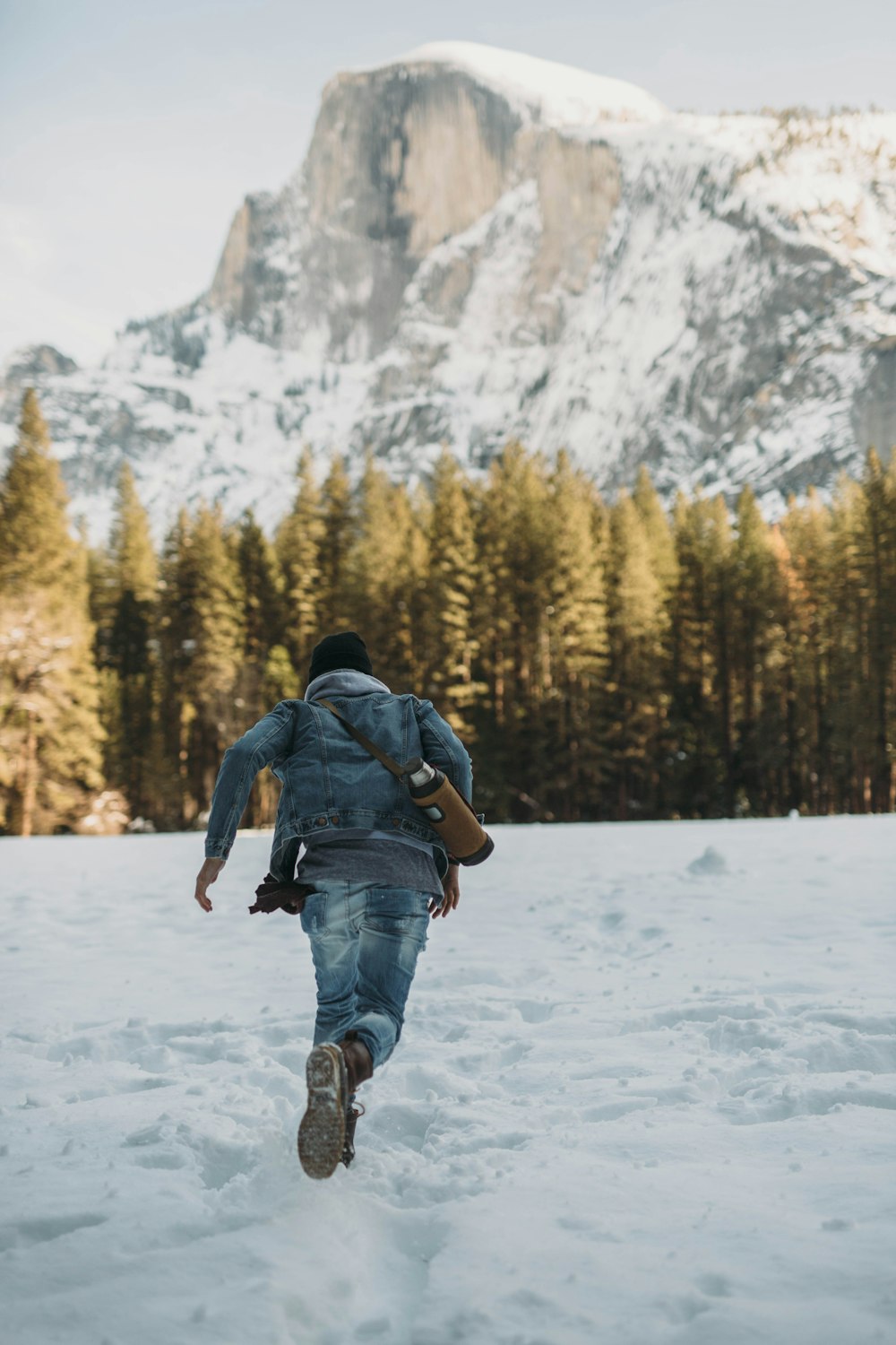 Hombre corriendo sobre la nieve cerca de la montaña nevada durante el día