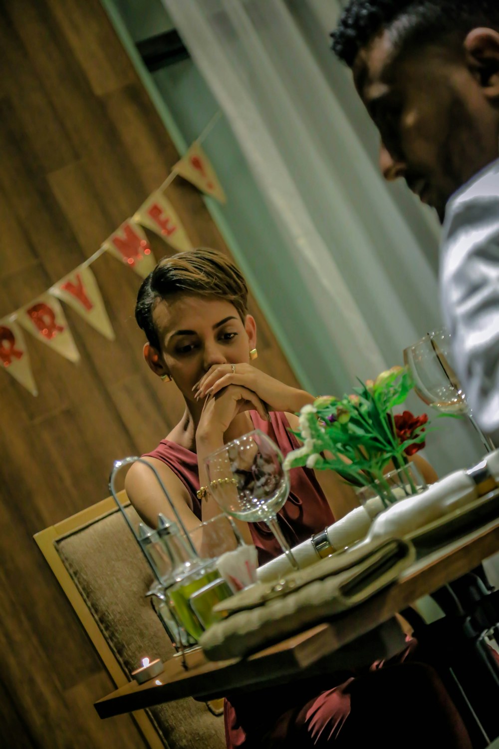 femme assise sur une chaise devant un verre de vin sur une table