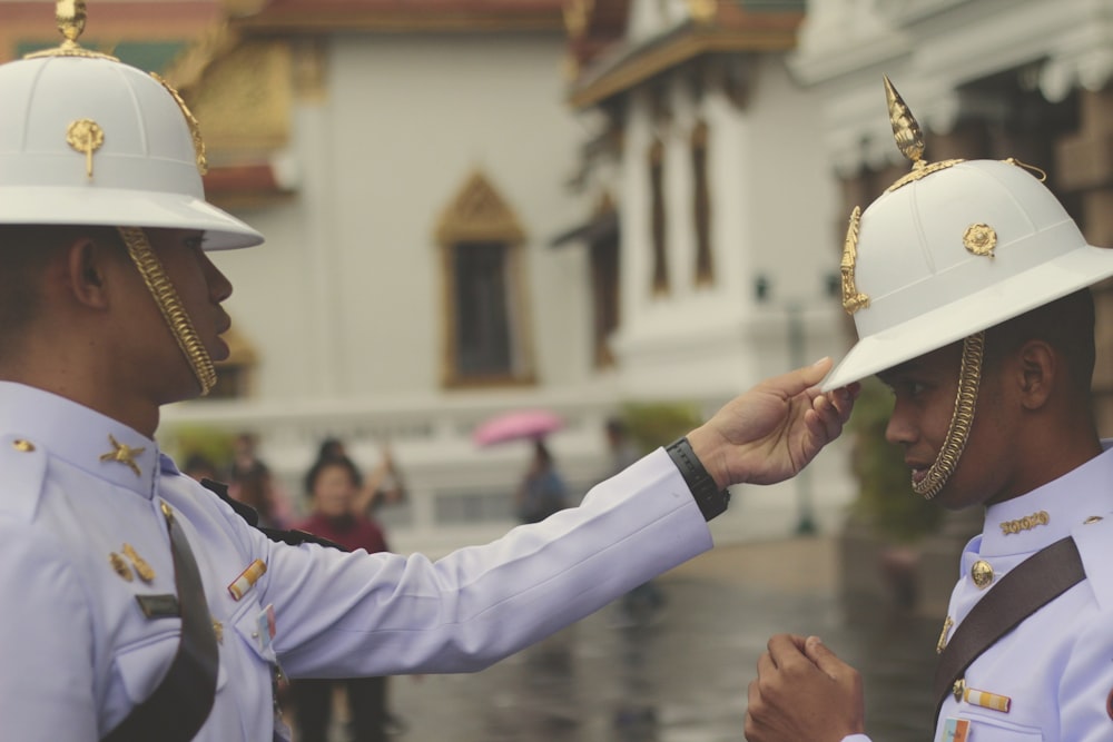 officer in white uniform touching man's white hat