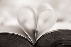 Um livro aberto com duas páginas suspensas dobradas formando a imagem de um coração