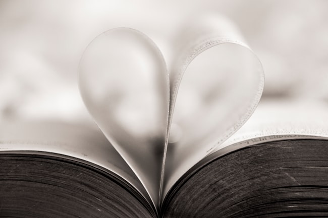 Um livro aberto com duas páginas suspensas dobradas formando a imagem de um coração