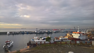 A busy harbor with ships docked and workers preparing for marine operations at sunrise.