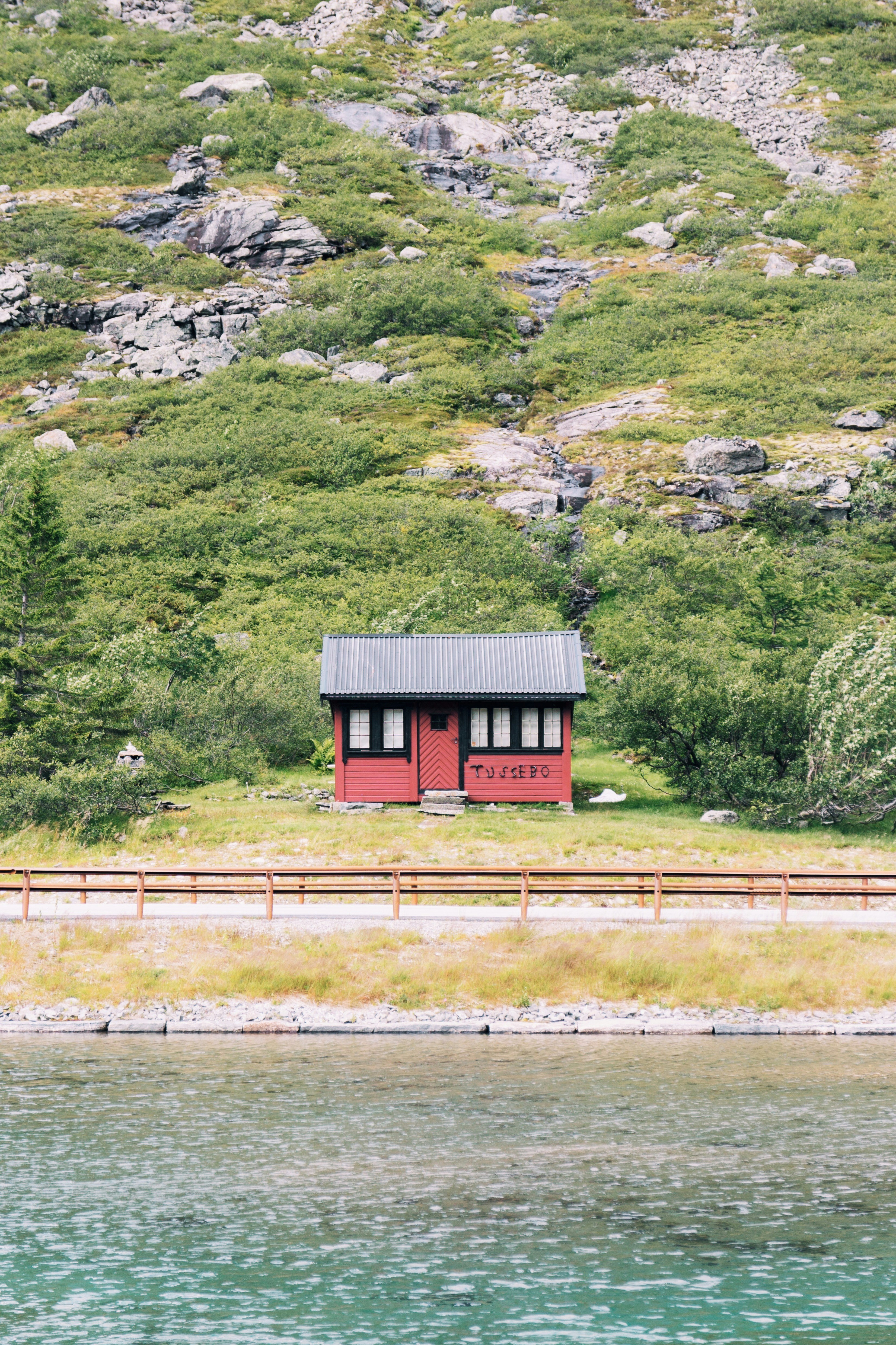 red and black wooden shack on hill near road