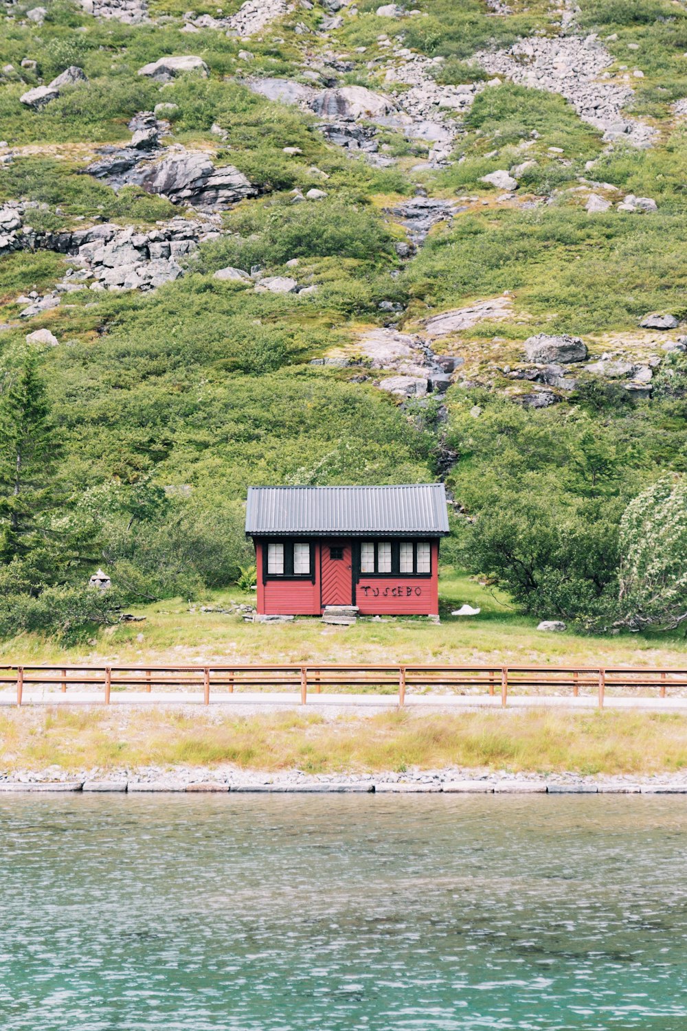 道路近くの丘の上にある赤と黒の木造の小屋