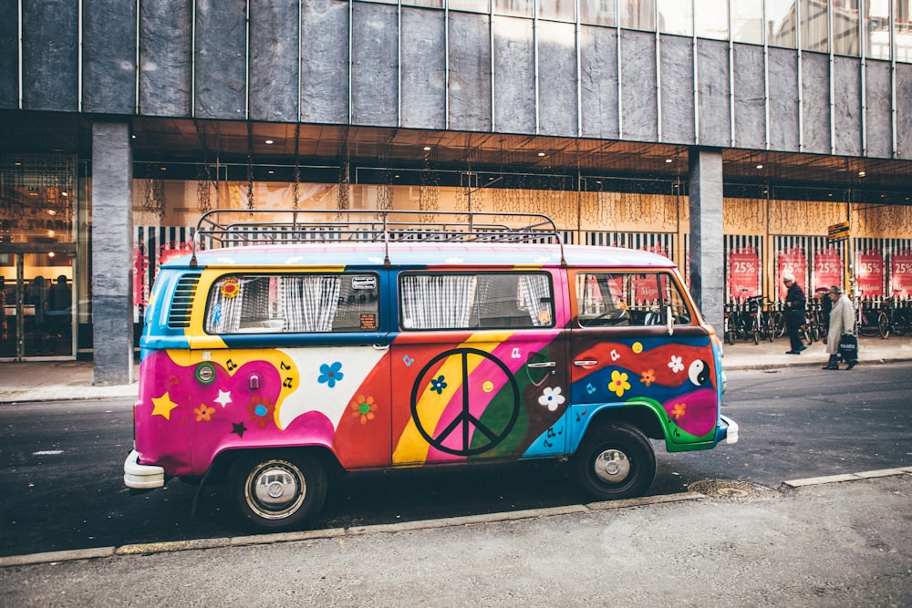 Minivan multicolor estacionada al costado de la carretera cerca del edificio