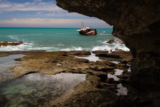brown and white fishing vessel near rock formation in Arniston South Africa