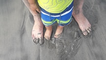 a young child standing in the sand on a beach