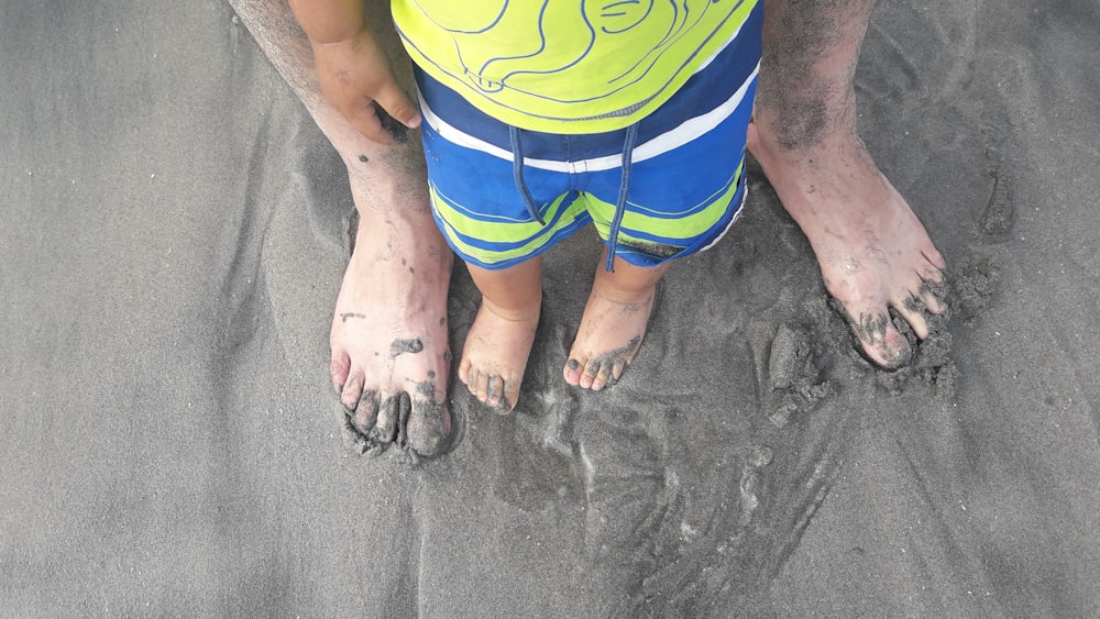 uma criança pequena em pé na areia em uma praia