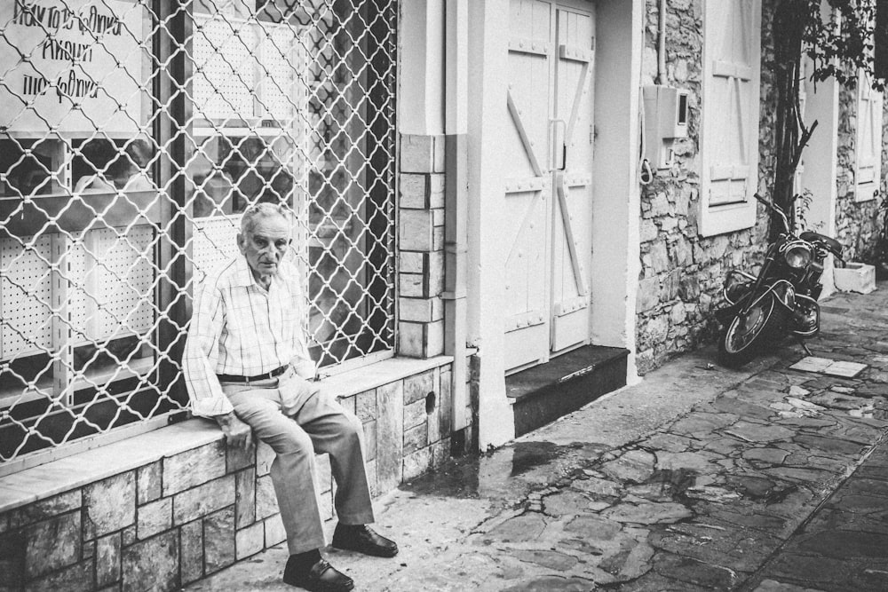 grayscale photography of man sitting on bench