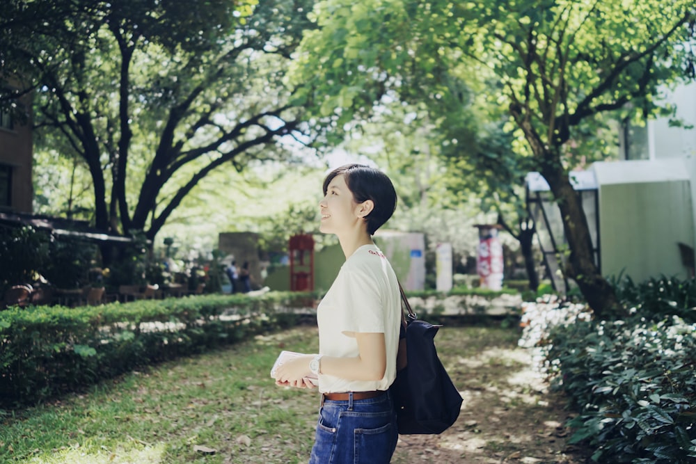 woman standing facing green tree