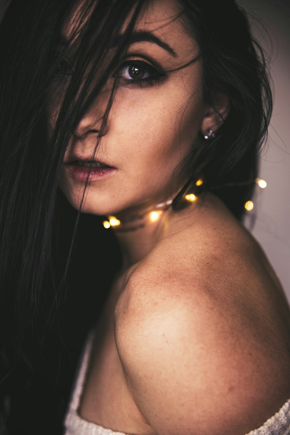 closeup photo of woman with string lights on neck