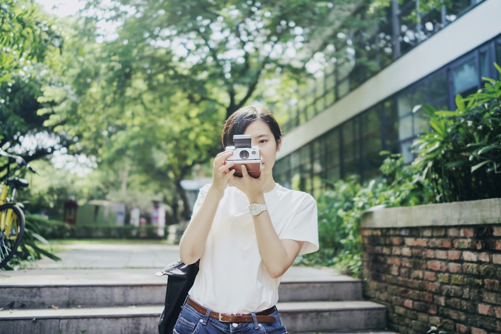 woman in white T-shirt using camera