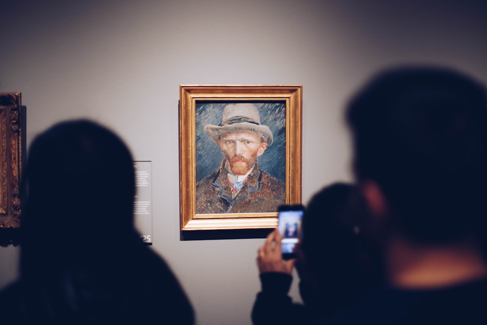 persona que toma la foto del hombre que lleva la pintura del sombrero marrón