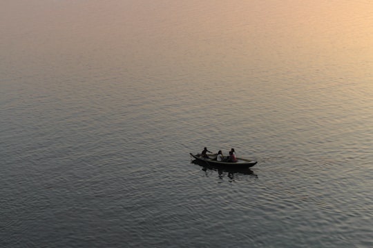 three person riding on boat surrounded by water during golden hour in Varanasi India