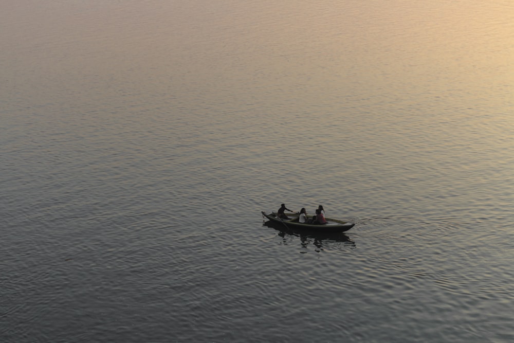 Tres personas montando en bote rodeado de agua durante la hora dorada